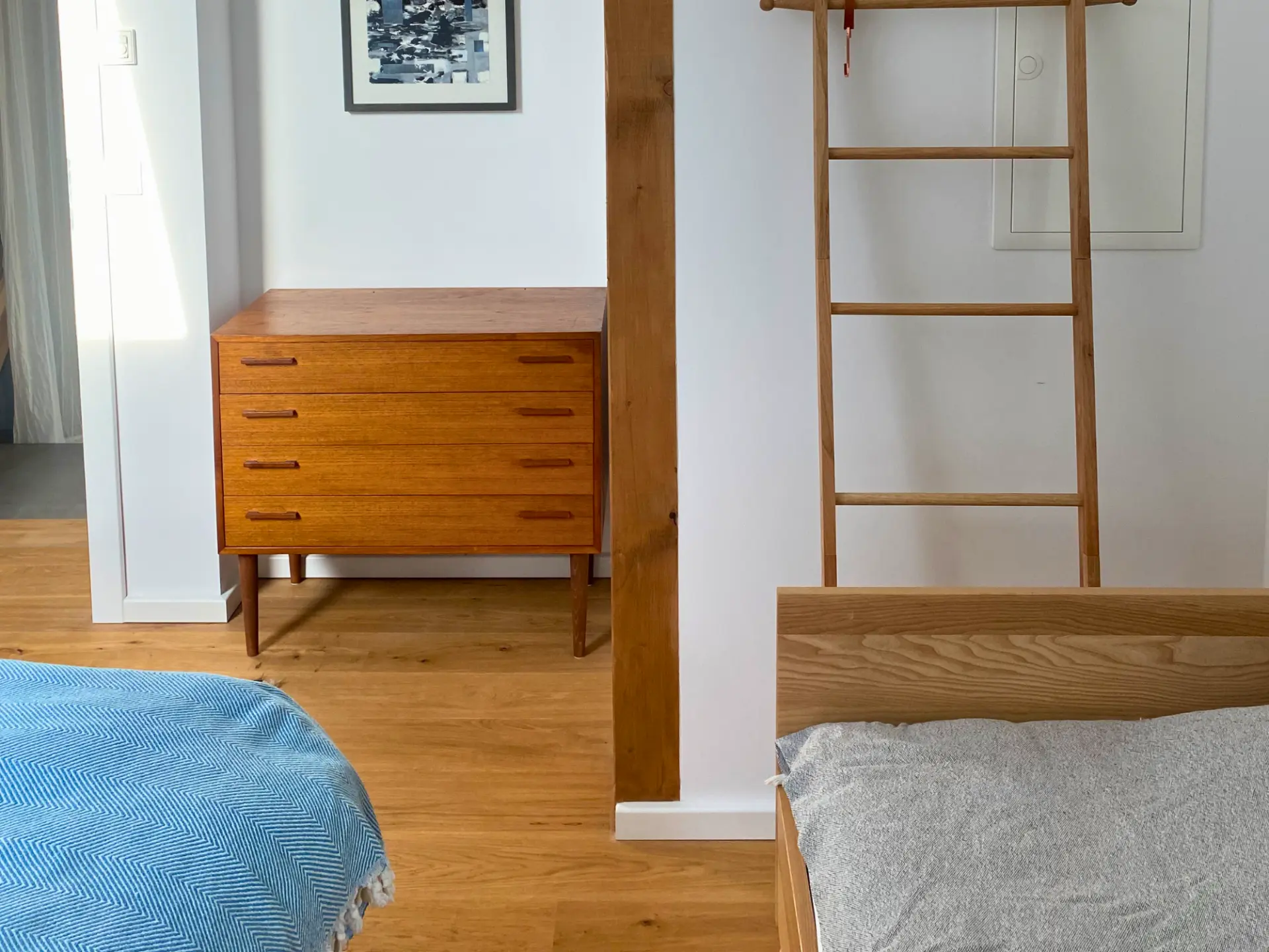 Detail aus dem Familienschlafzimmer: Holzbetten, Mid-Century-Kommode und ein Holzstützbalken mit Leiter