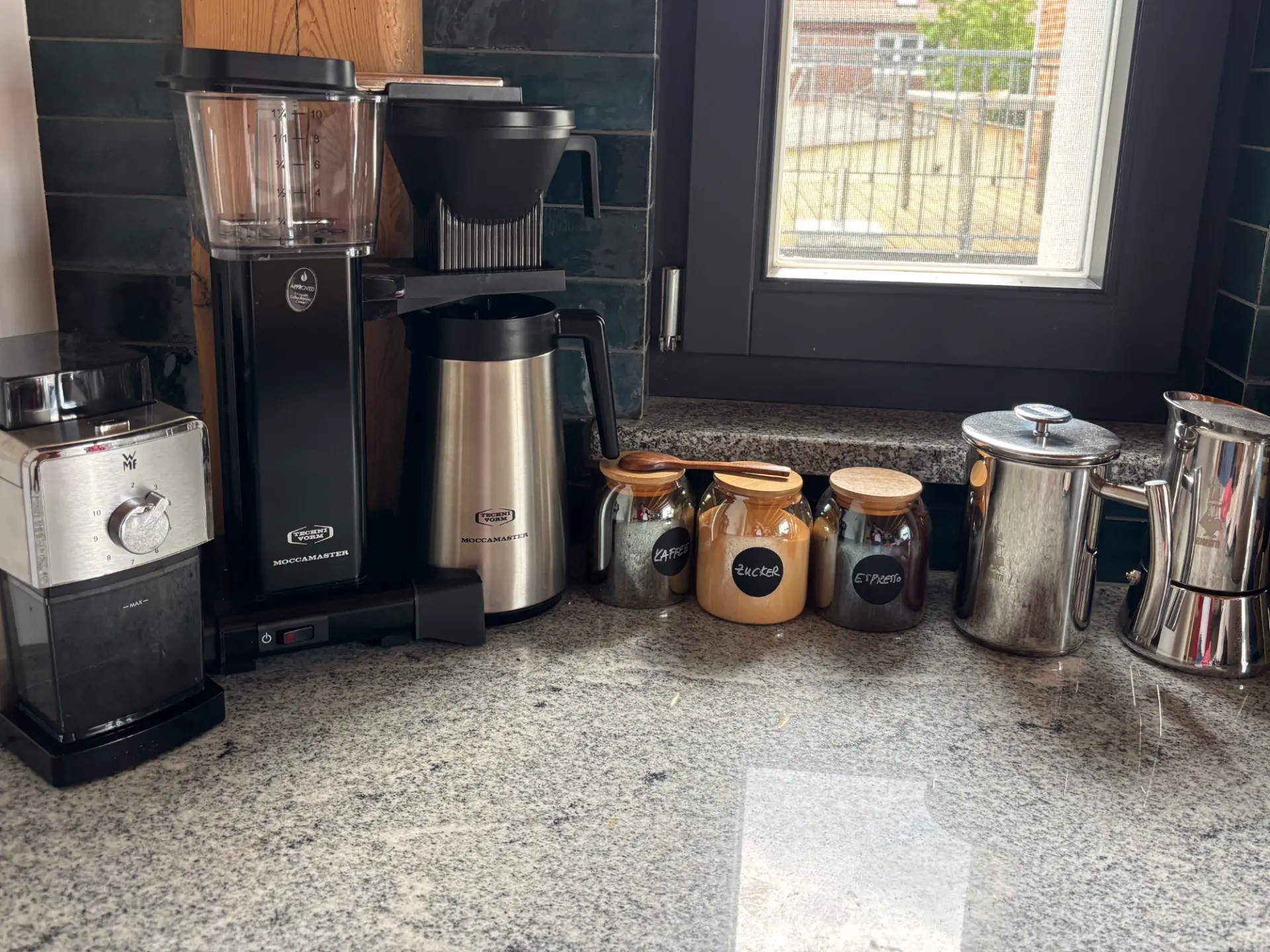 Kaffeeecke mit Filterkaffeemaschine, Kaffeemühle und Vorratsgläsern auf Granitplatte