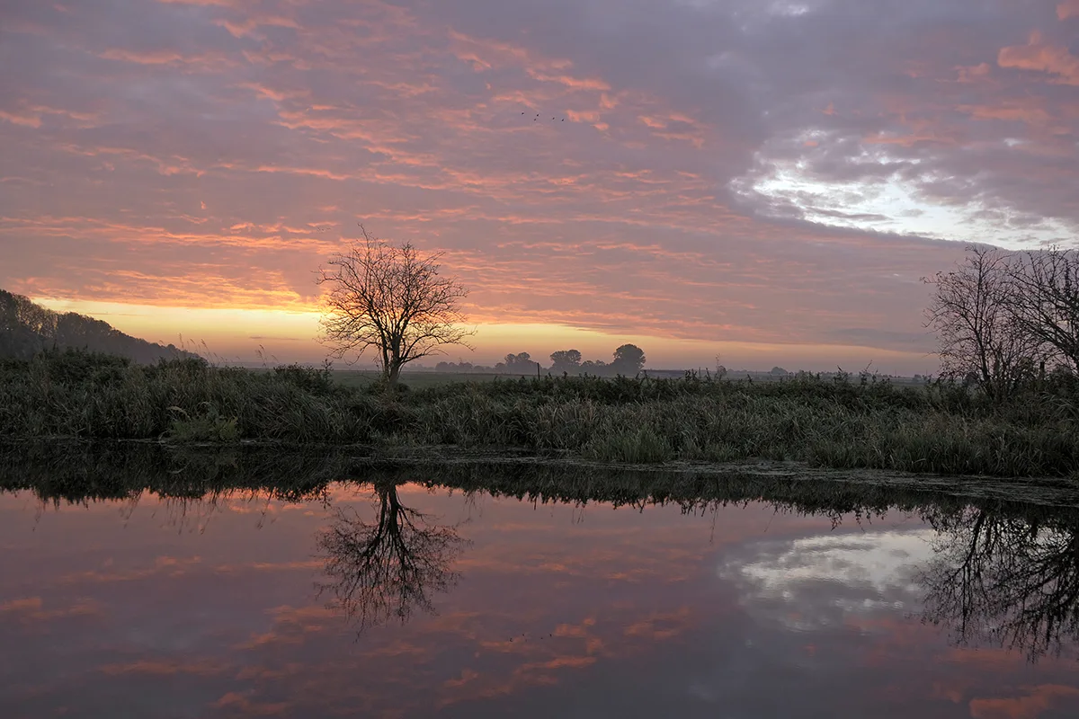 Sunrise on an early autumn morning on the outskirts of Linum, reflected in the water