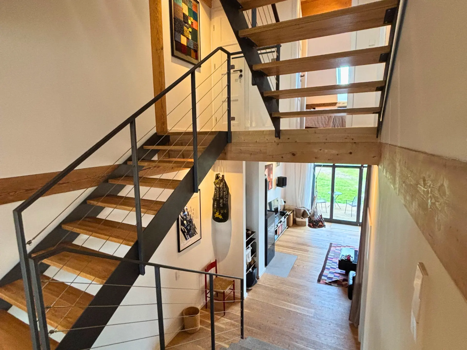 Offenes Treppenhaus mit Holzstufen und Seilgeländer, Blick hinab in den Wohnbereich